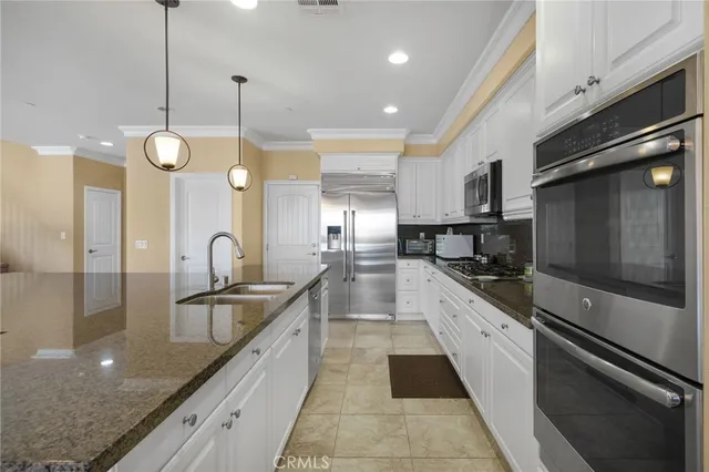 a large kitchen with granite countertop a sink a counter space appliances and cabinets