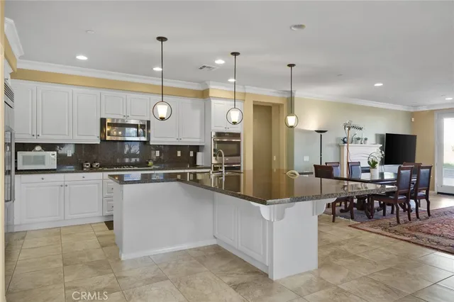 a kitchen with kitchen island granite countertop a stove a sink a oven a dining table and chairs