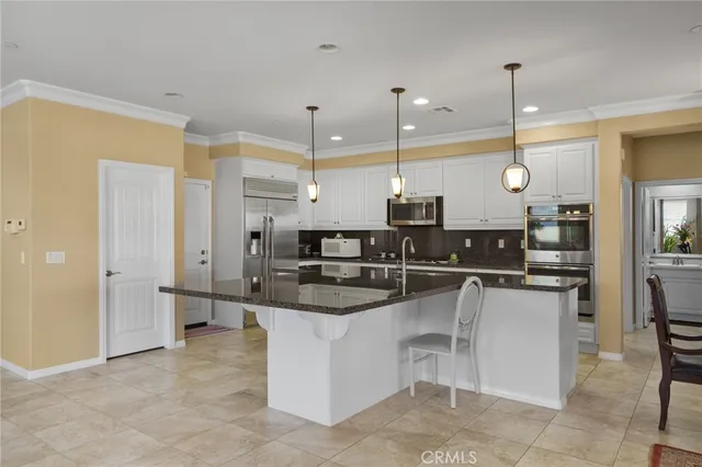 a kitchen with stainless steel appliances kitchen island a large counter top a stove a sink and a refrigerator