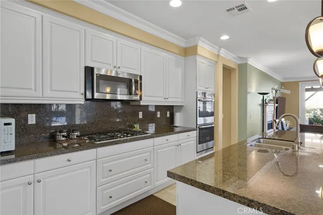 a kitchen with granite countertop a sink a stove and cabinets