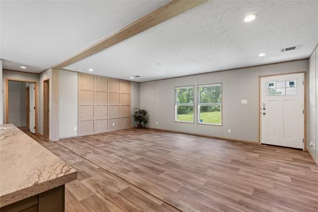 a view of empty room with wooden floor and windows