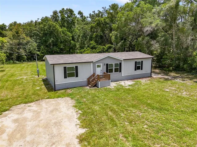 a view of a yard with plants and a bench