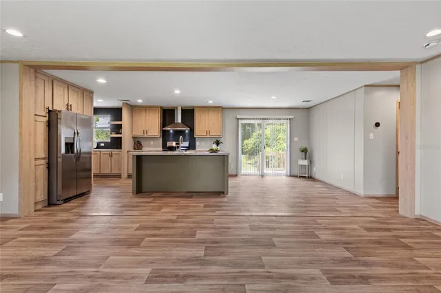 a view of kitchen with kitchen island a sink wooden floor and a refrigerator