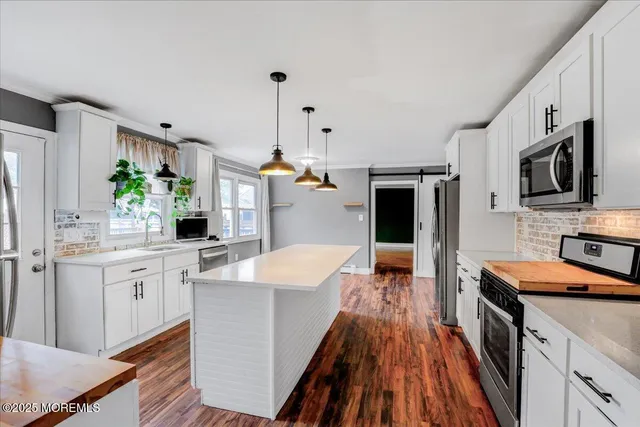 a large kitchen with stainless steel appliances granite countertop a lot of counter space and wooden floors