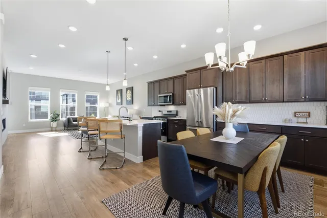 a kitchen with stainless steel appliances kitchen island granite countertop a table chairs and a refrigerator