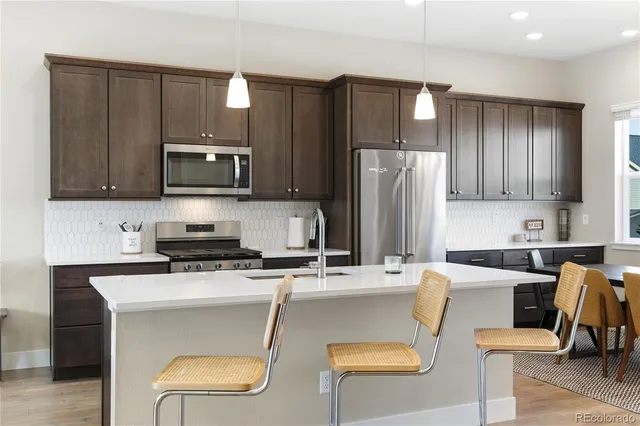 a kitchen with stainless steel appliances granite countertop a sink a stove and a wooden floors