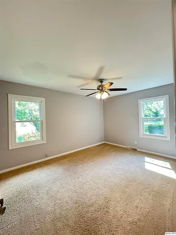an empty room with windows and fan