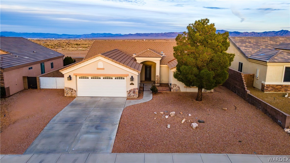 3374 Roma Road Kingman, AZ 86401 - Photo 22 of 64 View of front of home featuring a mountain view, driveway, stucco siding, an attached garage, and stone siding