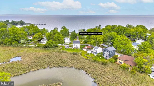 a kitchen with stainless steel appliances a refrigerator a stove a sink a dining table and chairs with wooden floor