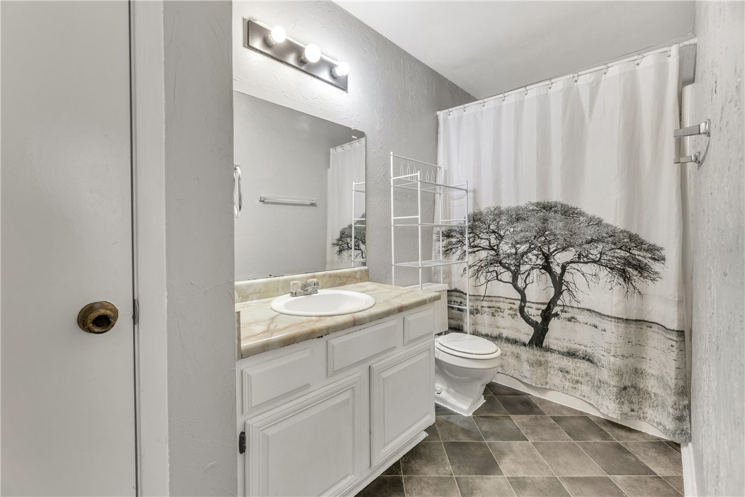 2101 Barak Lane, Unit 17 Bryan, TX 77802 - Photo 16 of 19 a bathroom with a granite countertop toilet a sink and a mirror