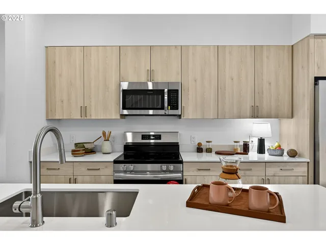 a kitchen with stainless steel appliances a sink a stove a microwave a sink a refrigerator and cabinets