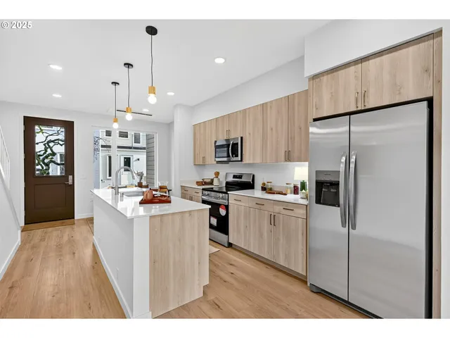 a kitchen with stainless steel appliances granite countertop a refrigerator a sink dishwasher a stove oven and white countertops with wooden floor