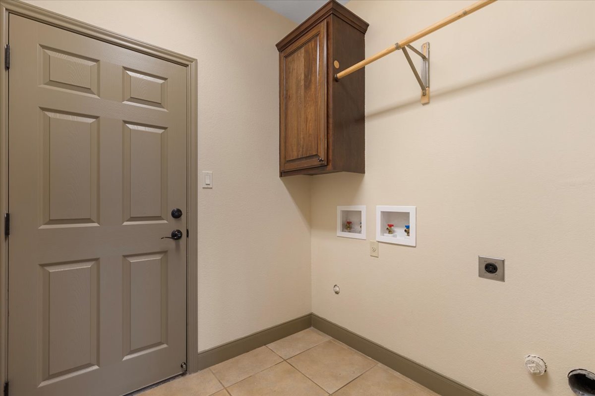 106 Spring Meadow Road Bastrop, TX 78602 - Photo 25 of 39 Washroom with hookup for a washing machine, hookup for an electric dryer, light tile patterned floors, gas dryer hookup, and cabinet space