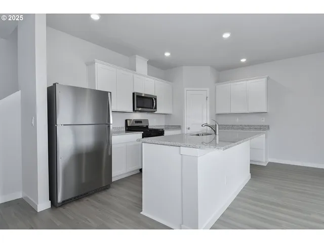 a kitchen with kitchen island a sink stainless steel appliances and refrigerator