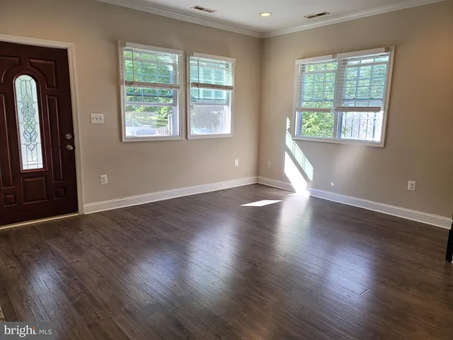 an empty room with wooden floor and windows