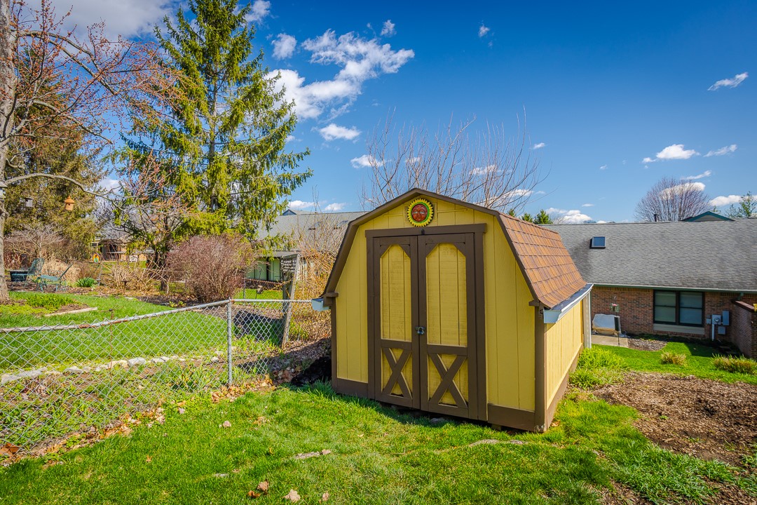 540 Basil Street Springboro, OH 45066 - Photo 28 of 32 This charming yellow shed offers practical storage in a lush, green yard.