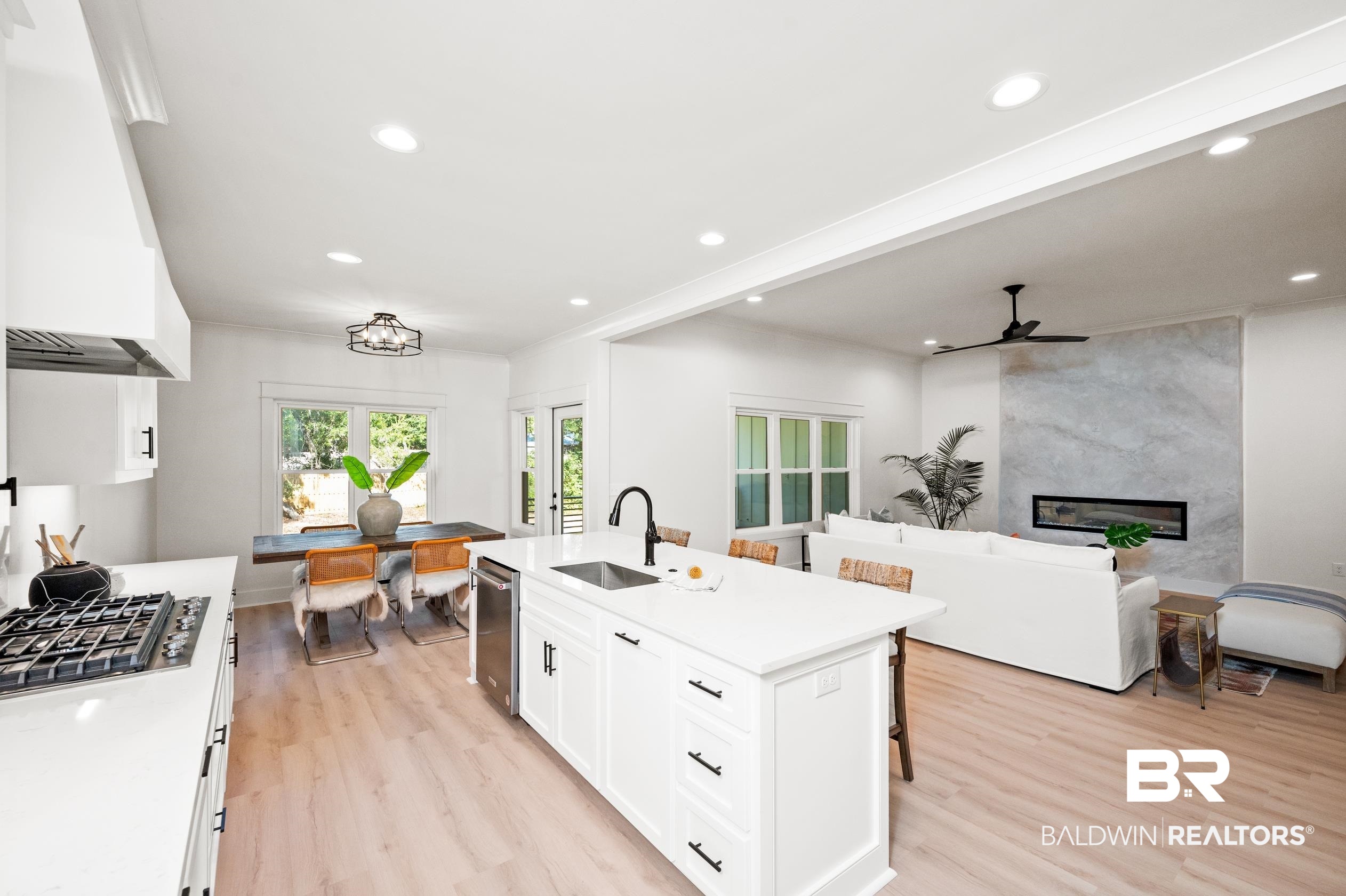 28889 Canal Road Orange Beach, AL 36561 - Photo 14 of 55 Kitchen featuring sink, an island with sink, stainless steel gas stovetop, white cabinets, and custom range hood