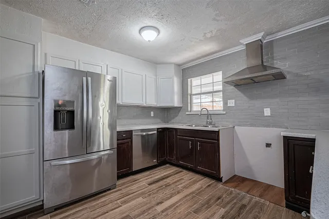 a kitchen with stainless steel appliances granite countertop a refrigerator a sink dishwasher a stove and white countertops with wooden floor