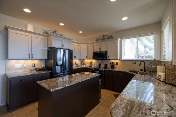 a kitchen with kitchen island granite countertop a sink stove refrigerator and cabinets