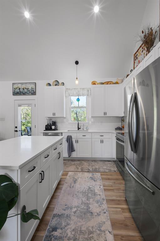 116 Lindsey Lane Runaway Bay, TX 76426 - Photo 15 of 35 a large white kitchen with stainless steel appliances granite countertop a refrigerator a sink dishwasher a stove and white countertops with wooden floor
