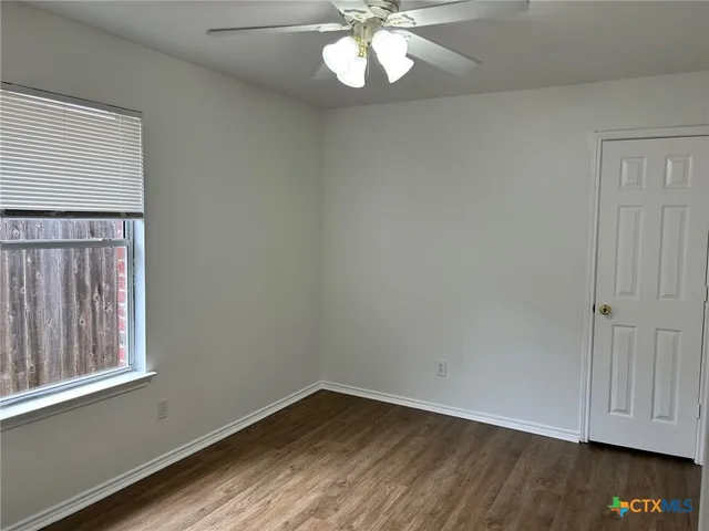 an empty room with wooden floor cabinet and windows