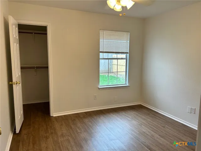 an empty room with wooden floor closet and windows