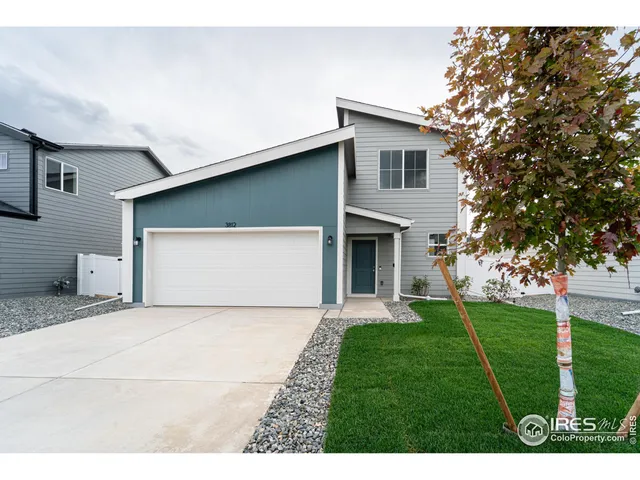 a view of a white house with a small yard and a large tree