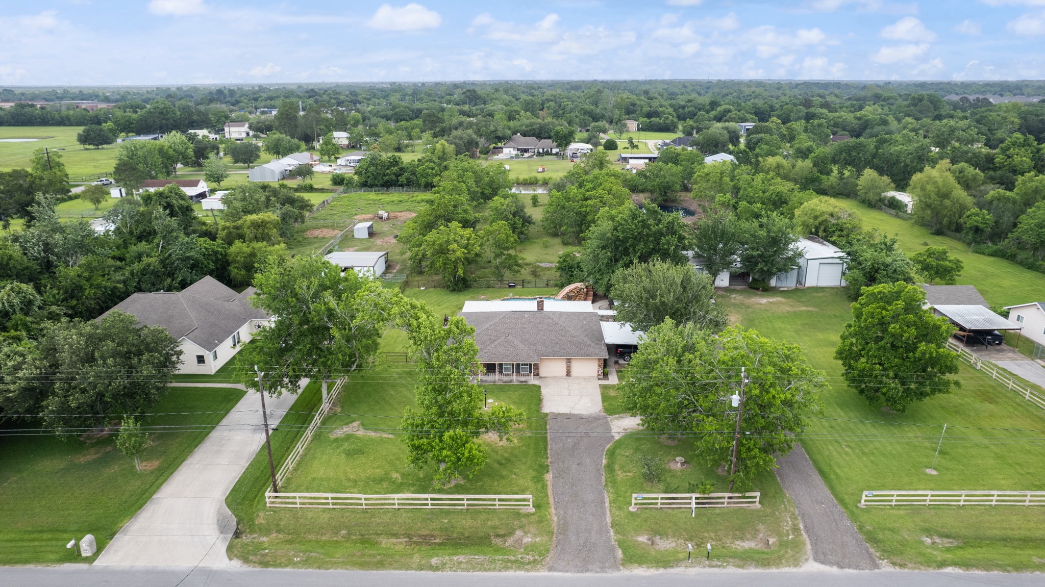15602 Fir Road Santa Fe, TX 77517 - Photo 40 of 42 Expansive aerial view showcasing the home, pool area, horse barn, insulated workshop, and sprawling acreage surrounded by mature trees. This unique property offers a blend of residential comfort, outdoor recreation, and functional space for hobbies or livestock.