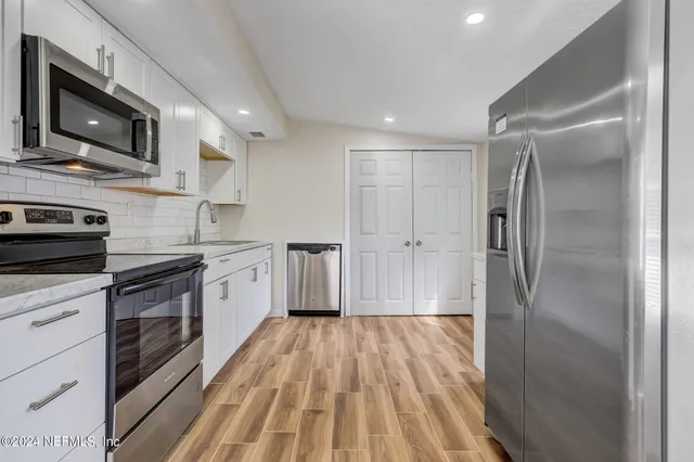 a kitchen with stainless steel appliances granite countertop a refrigerator a stove top oven a sink and dishwasher