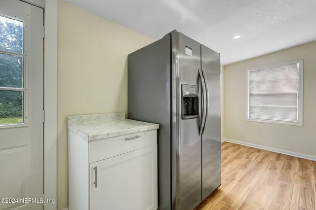 a kitchen with a refrigerator and countertop wooden floor