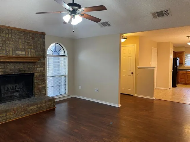 a view of empty room with wooden floor and a fireplace