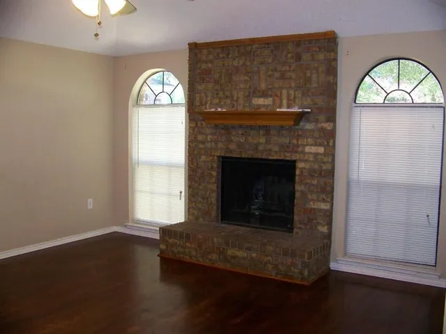 an empty room with a fireplace and wooden floor