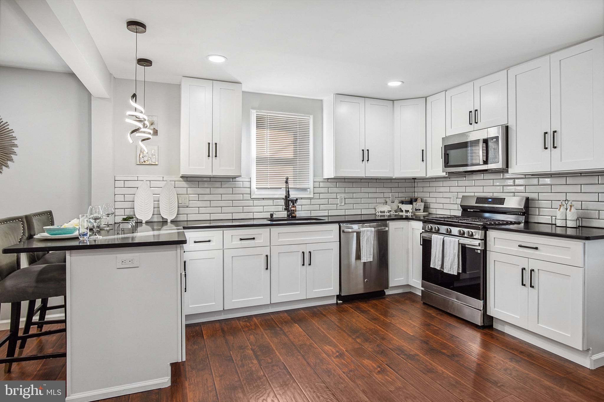 2501 North Point Road Dundalk, MD 21222 - Photo 7 of 28 a kitchen with granite countertop white cabinets and white stainless steel appliances