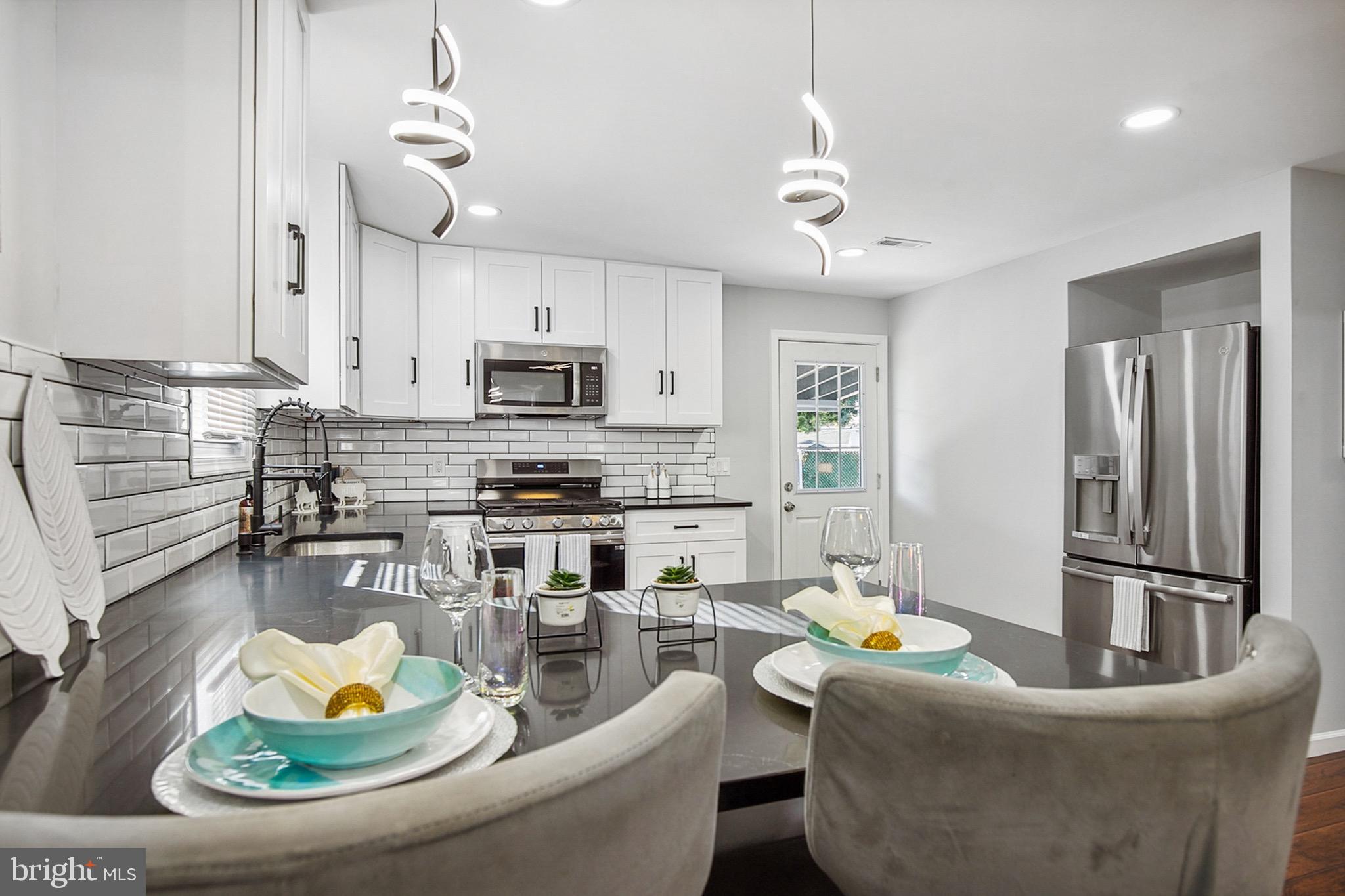 2501 North Point Road Dundalk, MD 21222 - Photo 9 of 28 a kitchen with stainless steel appliances granite countertop a stove a refrigerator a sink a dining table and chairs with wooden floor
