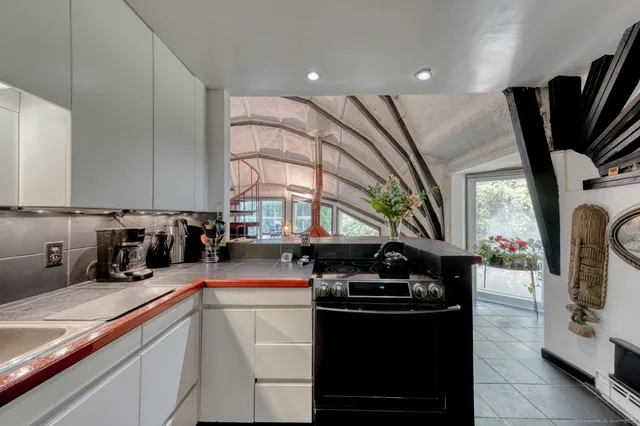 a kitchen with stainless steel appliances kitchen island granite countertop a sink a stove and a wooden floors