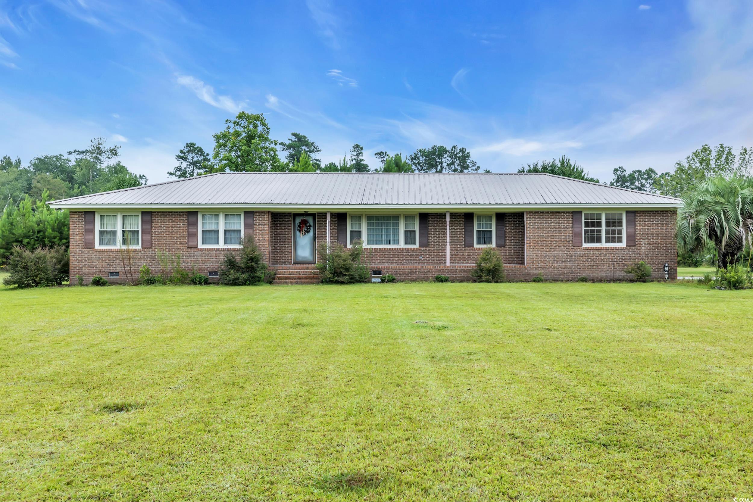 Ranch-style home featuring crawl space, brick siding, a front lawn, and a metal roof