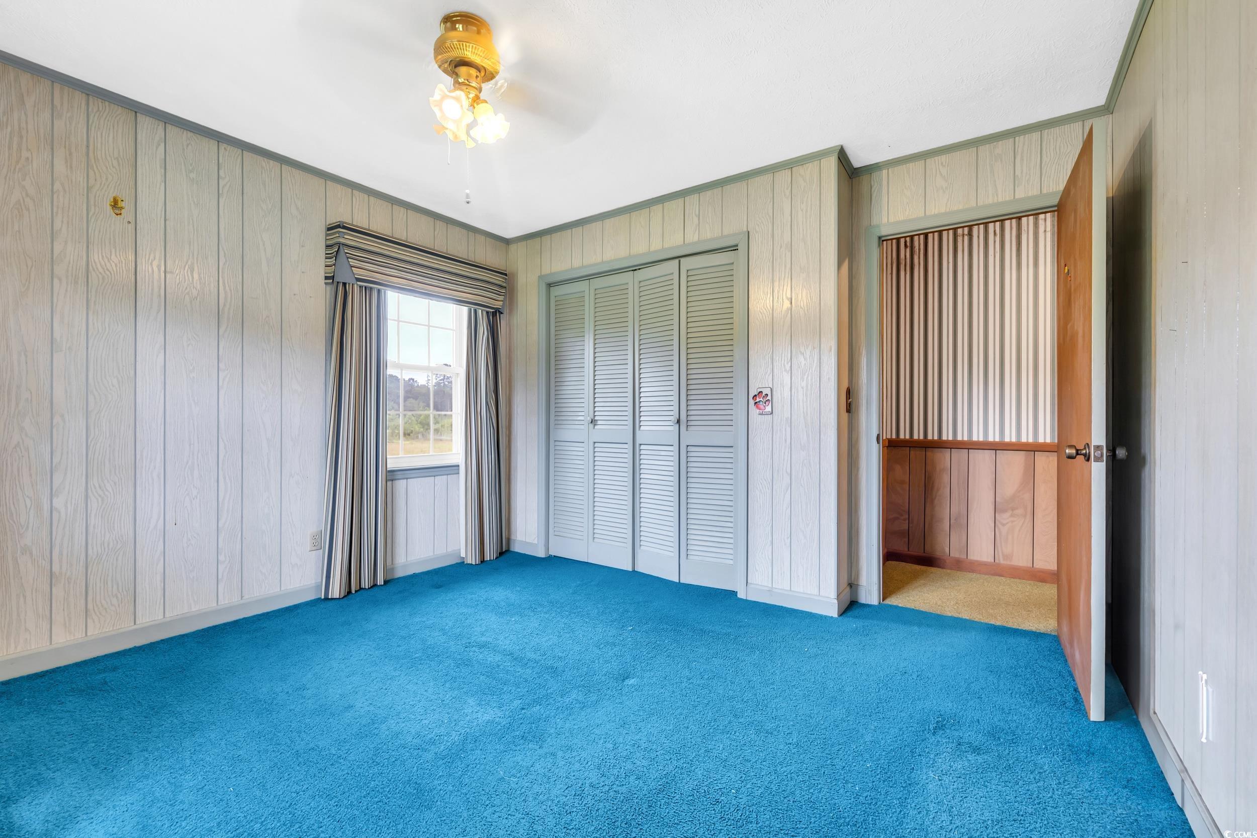 1928 Emery Road Loris, SC 29569 - Photo 13 of 24 Unfurnished bedroom featuring wooden walls, carpet floors, a closet, and a ceiling fan