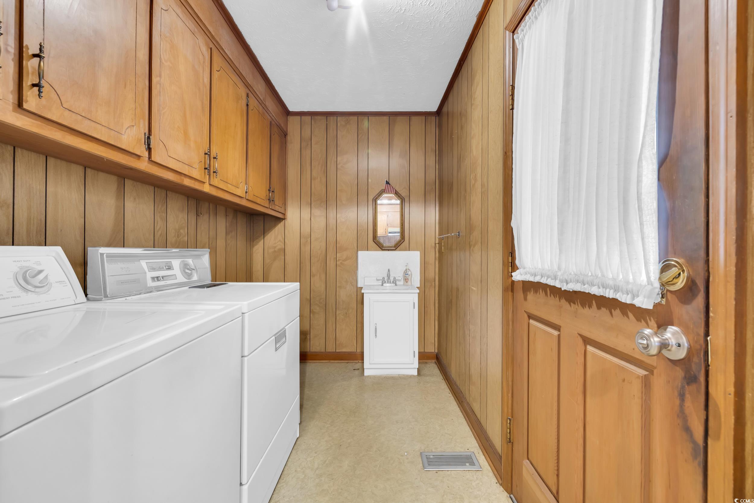 1928 Emery Road Loris, SC 29569 - Photo 18 of 24 Laundry room featuring wooden walls, washer and dryer, cabinet space, and light flooring