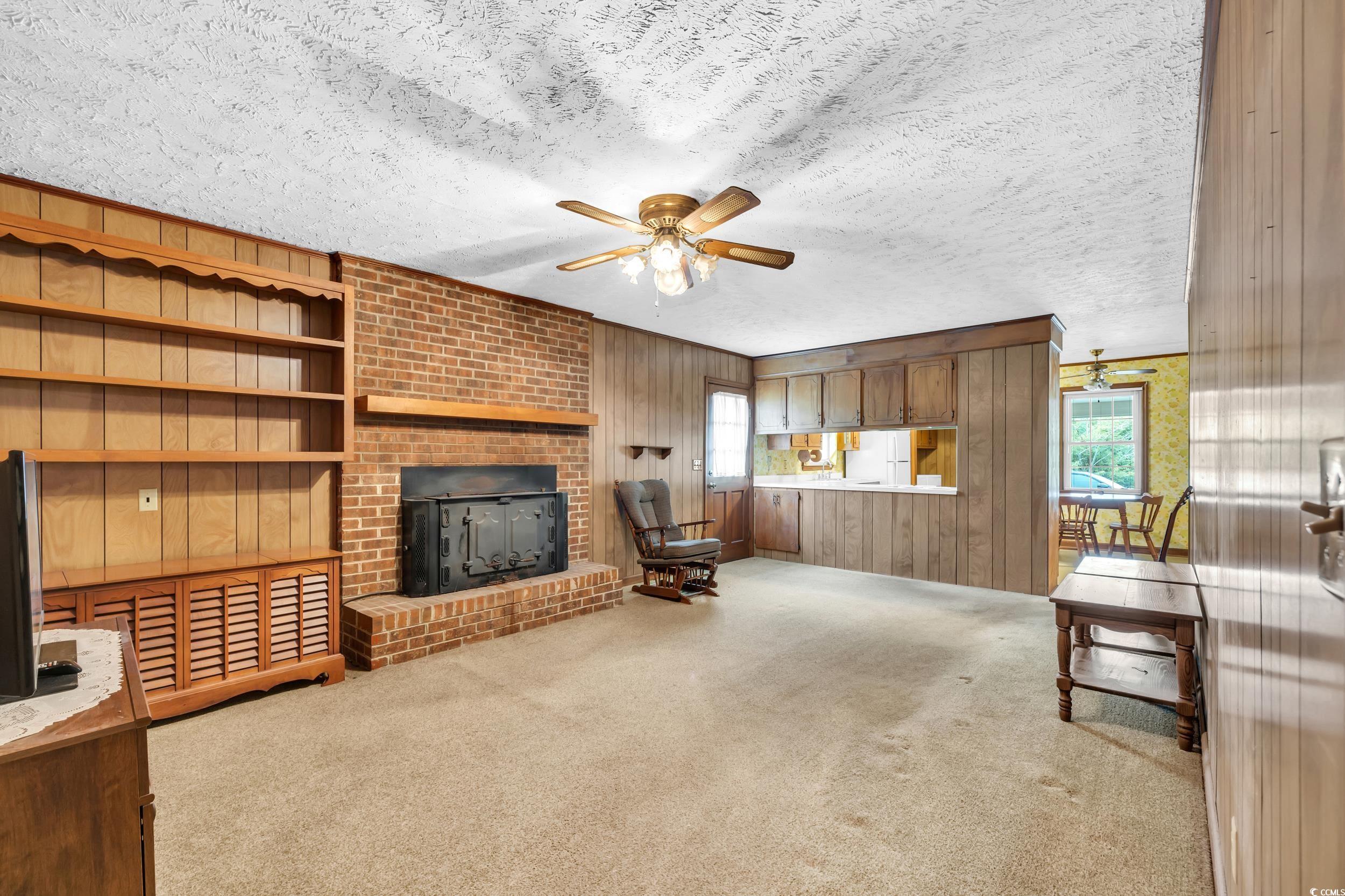 1928 Emery Road Loris, SC 29569 - Photo 4 of 24 Unfurnished living room with wood walls, light carpet, a textured ceiling, and a ceiling fan