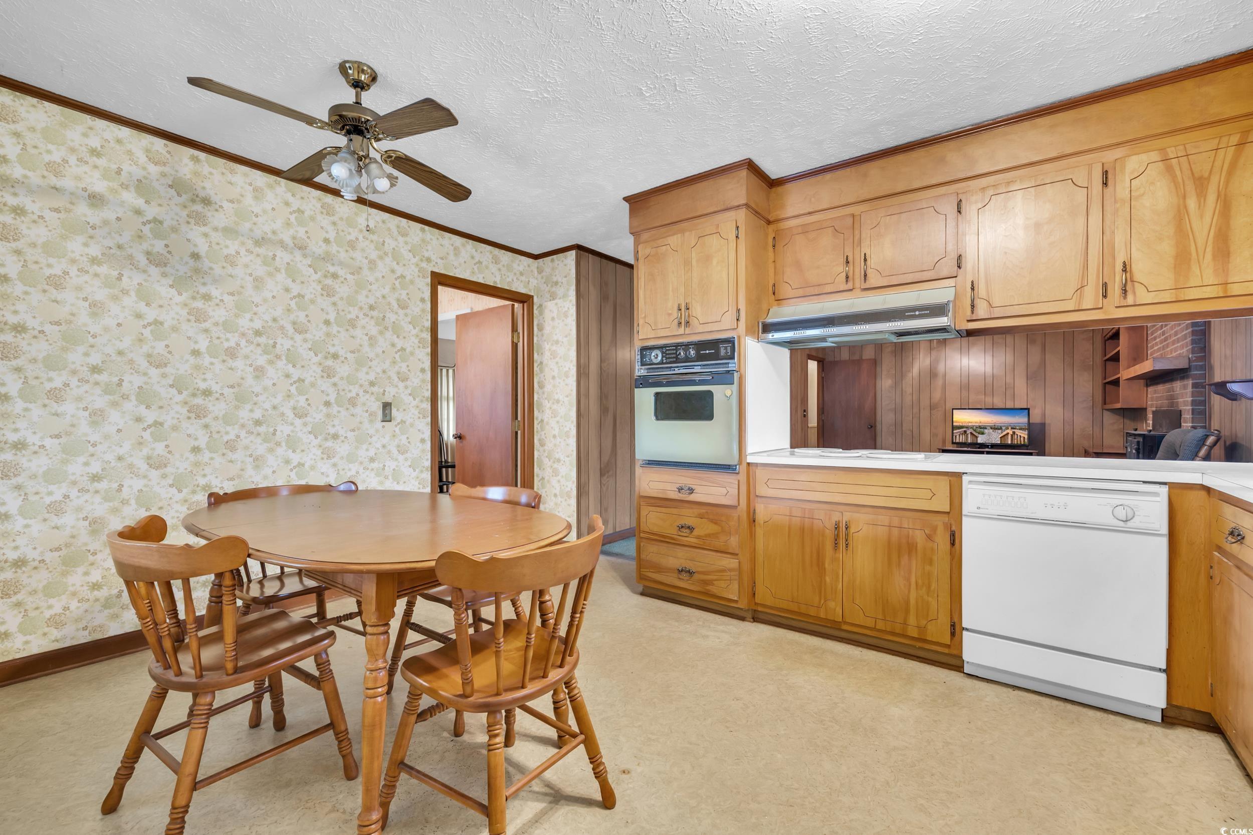 1928 Emery Road Loris, SC 29569 - Photo 5 of 24 Kitchen featuring white dishwasher, light countertops, ornamental molding, under cabinet range hood, and a textured ceiling
