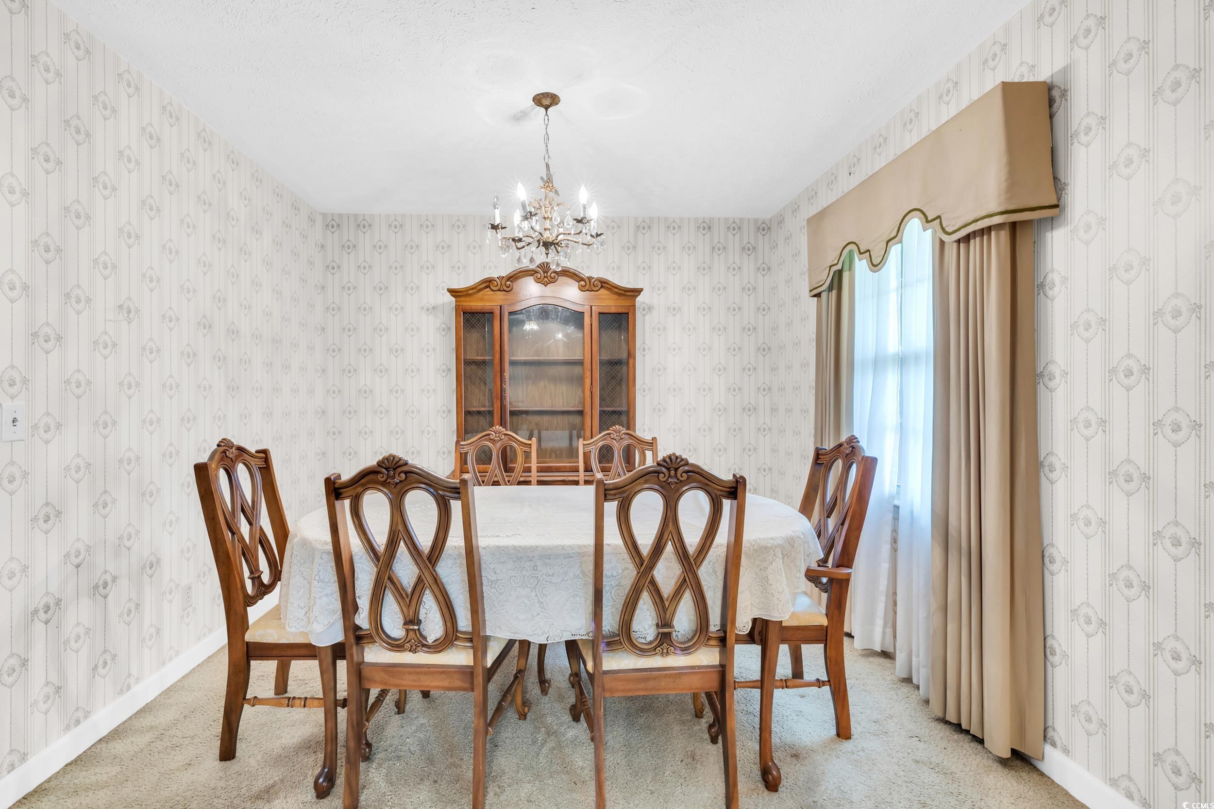 1928 Emery Road Loris, SC 29569 - Photo 7 of 24 Dining area featuring a chandelier, wallpapered walls, and carpet