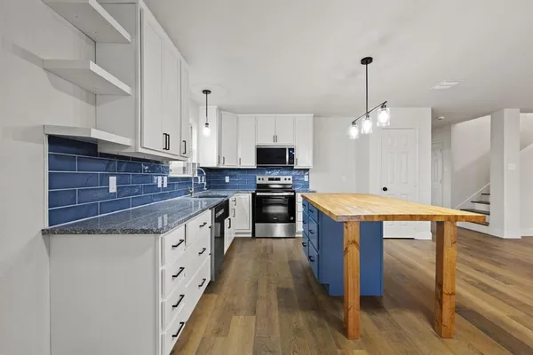 a kitchen with stainless steel appliances granite countertop wooden cabinets a sink dishwasher a stove and a refrigerator