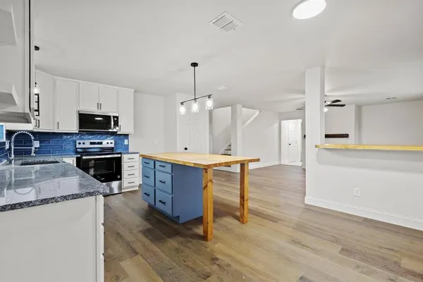 a large kitchen with a center island wooden floor stainless steel appliances and cabinets