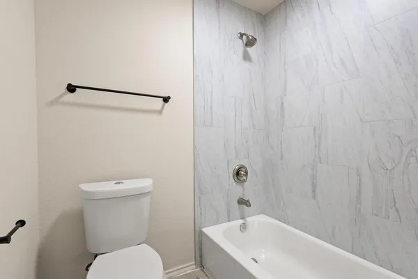 a white toilet sitting next to a white bath tub