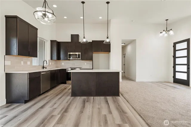 a large kitchen with stainless steel appliances a large counter top a stove and a sink