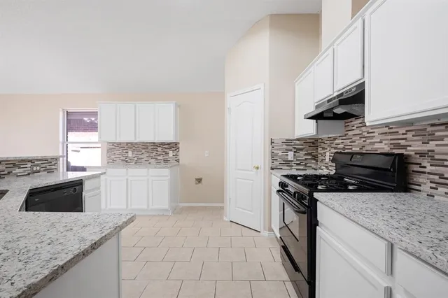 a kitchen with granite countertop a stove sink and cabinets