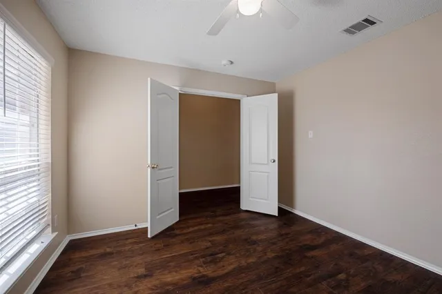 an empty room with wooden floor and windows