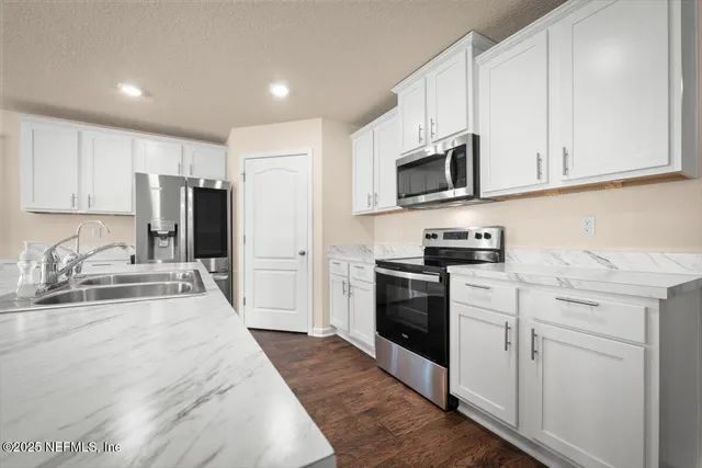 a kitchen with granite countertop a refrigerator stove top oven and sink
