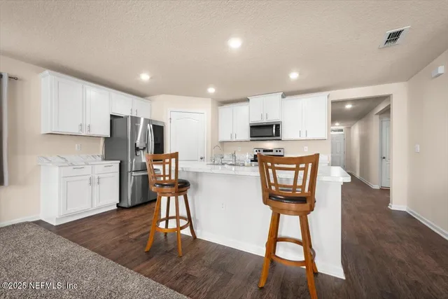 a kitchen with stainless steel appliances a refrigerator a stove a sink dishwasher and a dining table with wooden floor