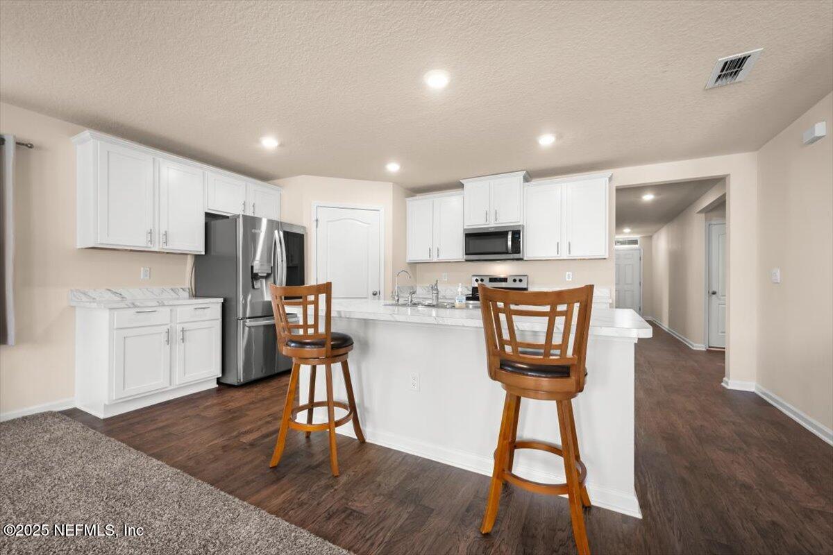 2080 Denton Trace Green Cove Springs, FL 32043 - Photo 14 of 32 a kitchen with stainless steel appliances a refrigerator a stove a sink dishwasher and a dining table with wooden floor